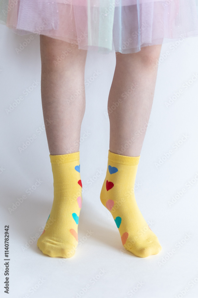 beautiful feet in warm socks with a hearts print on a white background close up. beautiful feet in warm socks with a hearts print on a white background close up.