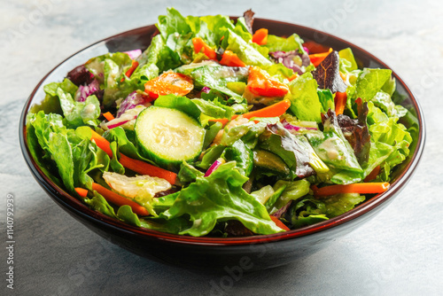 Fresh garden salad with mixed greens, cucumbers, and carrots in a brown bowl