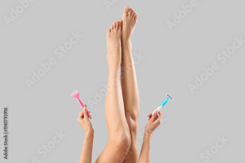 Legs of beautiful young woman with razors on grey background, closeup