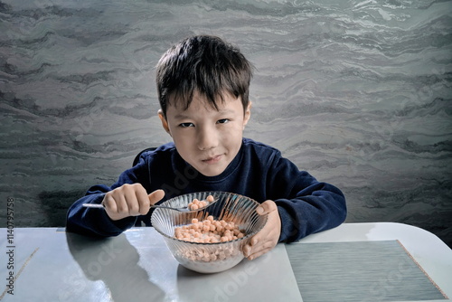 Sleepy little boy with a dissatisfied face eating cereal