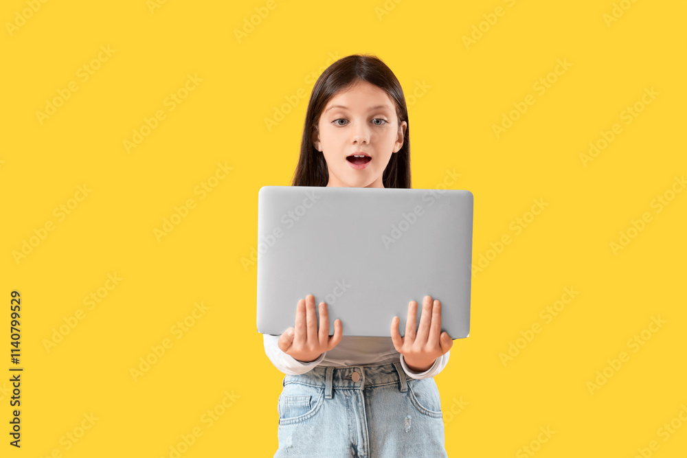 Shocked teenage girl with laptop on yellow background Shocked teenage girl with laptop on yellow background