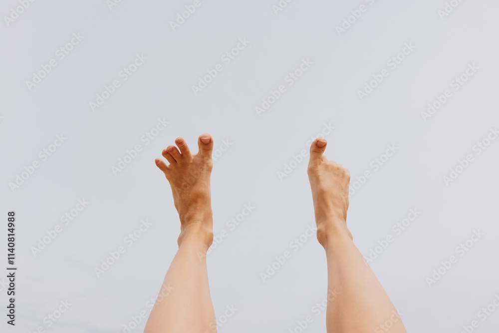 Person's legs up in the air with feet on the ground and hands raised, looking up at the sky Person's legs up in the air with feet on the ground and hands raised, looking up at the sky