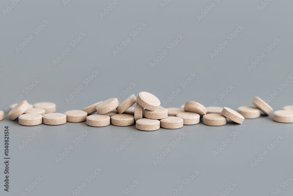 Pile beige herbal pills in a line on grey close up. Taking dietary supplements and vitamin Pile beige herbal pills in a line on grey close up. Taking dietary supplements and vitamin