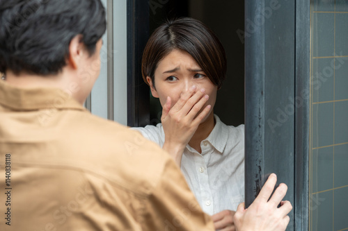 玄関先で訪問者に怯える女性
