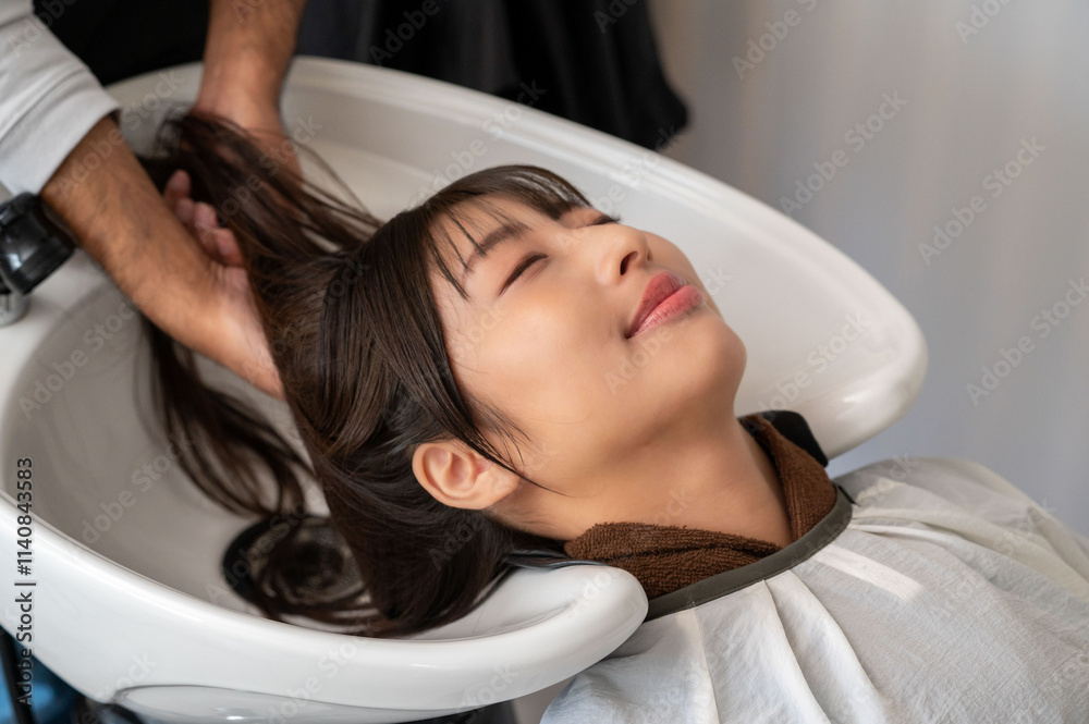 Obraz premium 男性スタッフに髪を洗ってもらう女性客