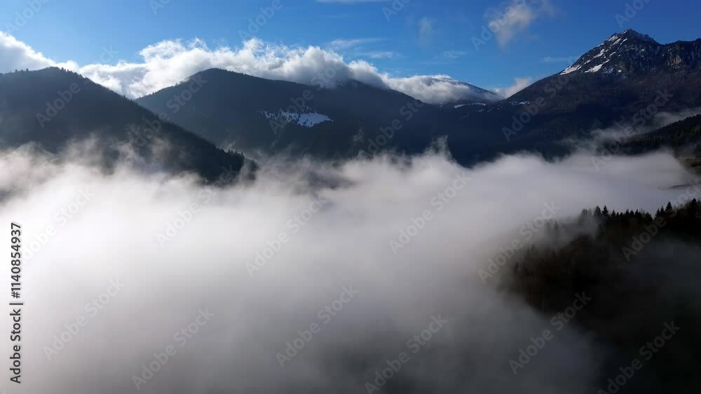 Aerial hyperlapse of mountain ridge rising above clouds at sunrise, valley fog below, timelapse