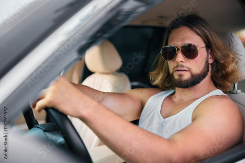 Confident man driving a car with sunglasses and relaxed demeanor photo