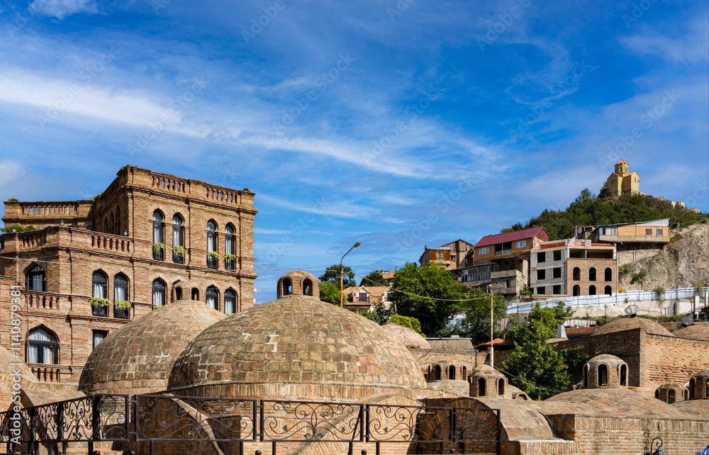 Bathhouses with brick domes in historic bath district in Tbilisi, with Tabori Hill with monastery in the background