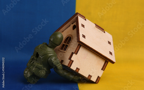 figurine of a soldier without a ern dragging a house on the flag of Ukraine photo