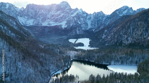 Lago di Fusine and Lago di Fusine Superiore, nestled in the Italian Alps, reveal their enchanting winter beauty when viewed from the air. Surrounded by snow-capped peaks and dense forests photo