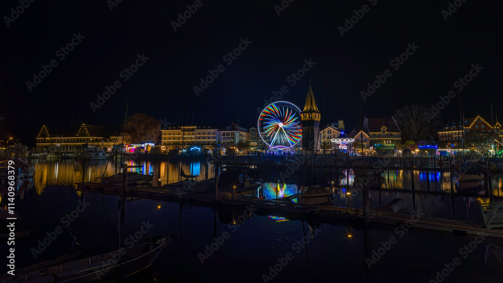Fototapeta premium Panoramaaufnahme eines Jahrmarkts in Lindau am Hafen, bei Nacht, mit Riesenrad und Kettenkarussell.