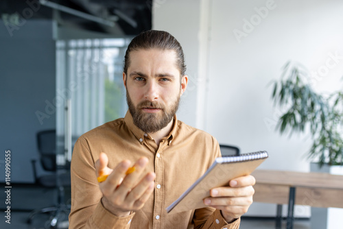 Papier peint Focused professional man holding a notebook, looking judgmental, inquisitive, an