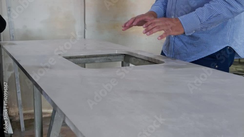 Experienced male quality control inspector examining and touching glossy surface of polished marble slab at quartz stone factory. Manufacturing kitchen countertop quartz