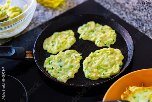 Cooking delicious zucchini pancakes in a frying pan photo