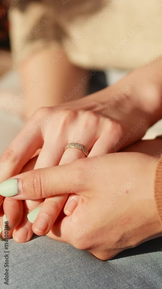 LGBT Pride Month, Gay Pride Symbol. Close up oh female hands of two lesbian girls sitting outdoors. Caring young woman holding hand supporting her girlfriend or wife give empathy care love. LGBT Pride Month, Gay Pride Symbol. Close up oh female hands of two lesbian girls sitting outdoors. Caring young woman holding hand supporting her girlfriend or wife give empathy care love.