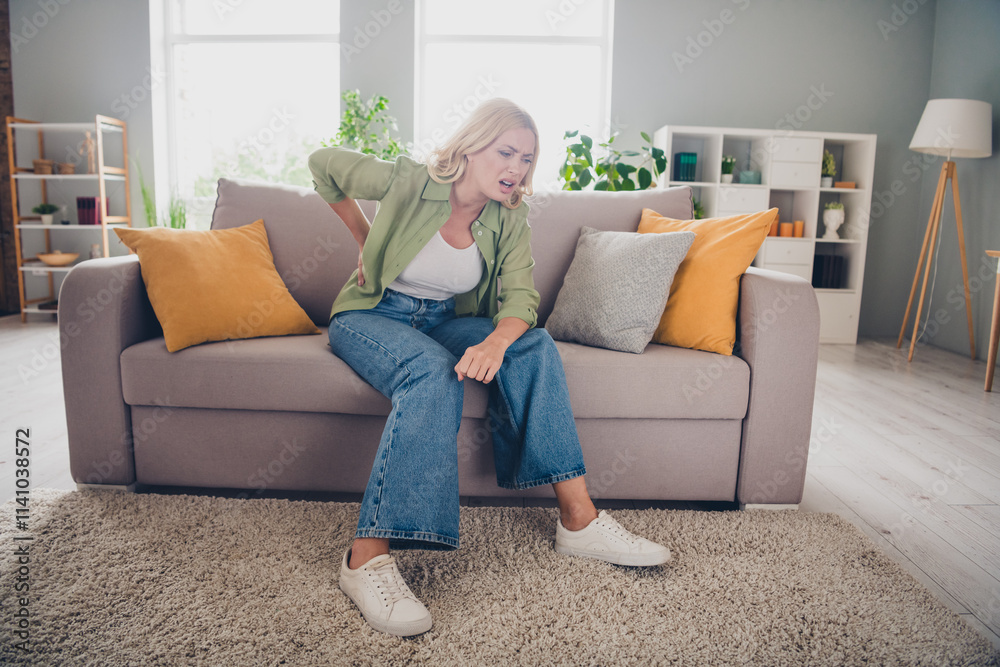 Middle-aged woman experiencing back pain in a cozy living room setting
