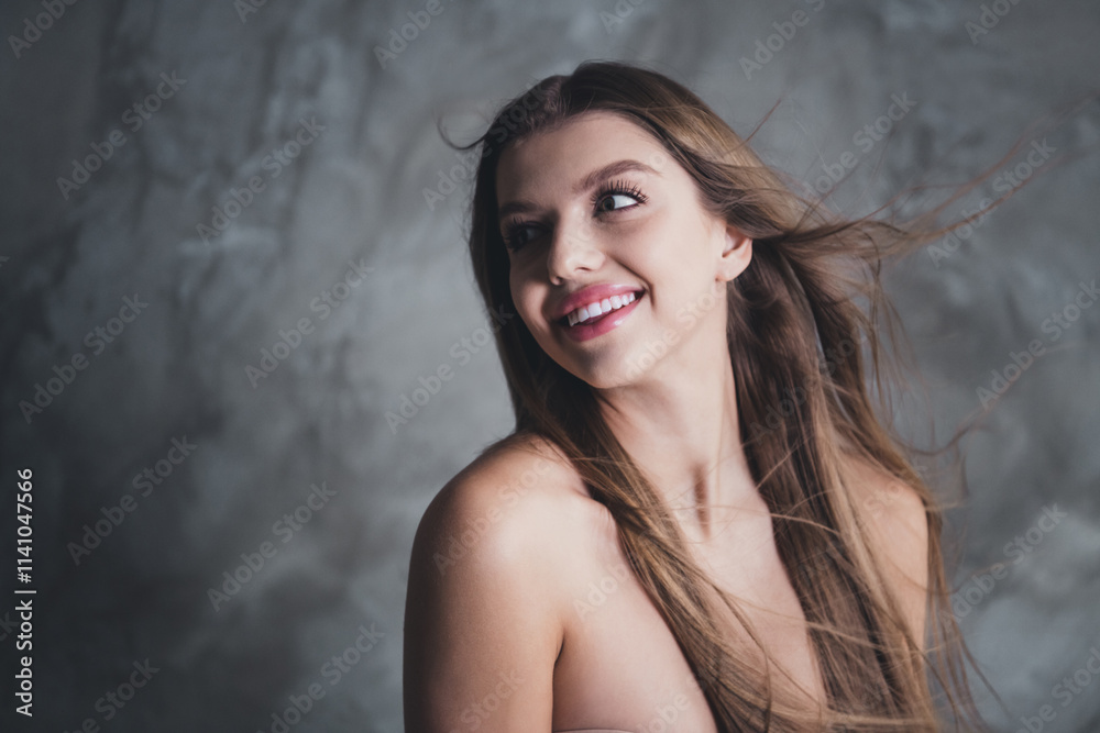 Charming young woman with blond hair posing in studio against grey background, embracing beauty and freedom Charming young woman with blond hair posing in studio against grey background, embracing beauty and freedom