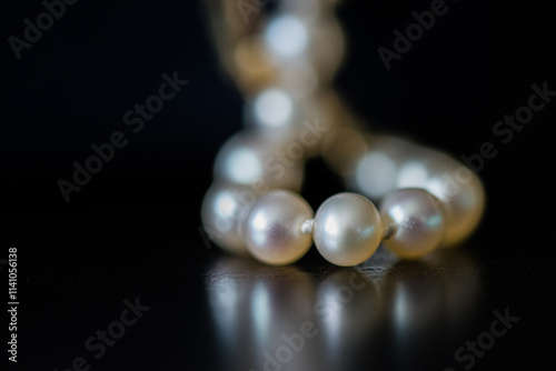 Close-up of pearl necklace in front of a black background