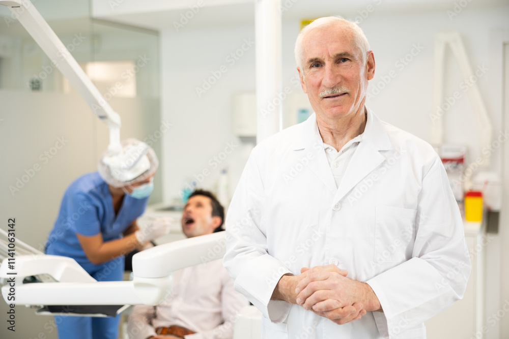 Obraz premium Mature man dentist posing while examining patient in dental clinic