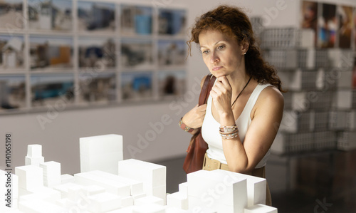 Photos Thoughtful woman in her middle ages gazing at displayed city models in exhibitio