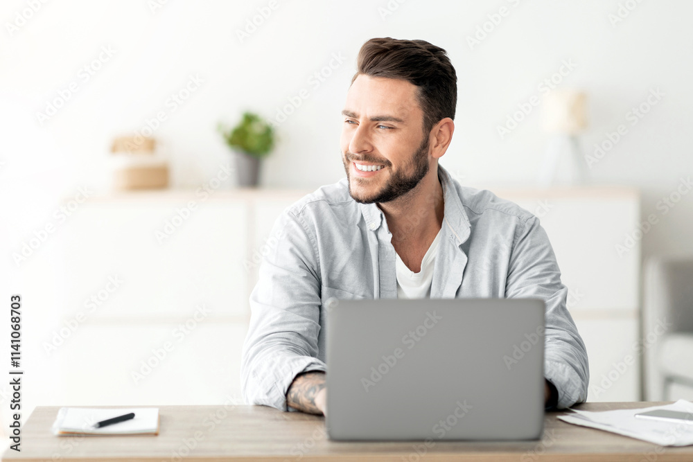 Happy freelance man working on laptop in home office, sitting on workplace and looking aside at free space. Smiling guy thinking about successful business strategy or dreaming about holiday Happy freelance man working on laptop in home office, sitting on workplace and looking aside at free space. Smiling guy thinking about successful business strategy or dreaming about holiday