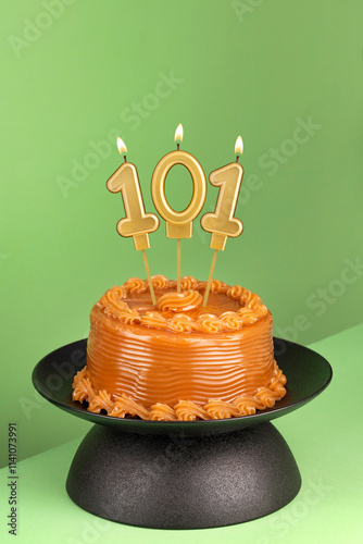 Delicious cake with dulce de leche - Number 101 birthday candle on a green background.