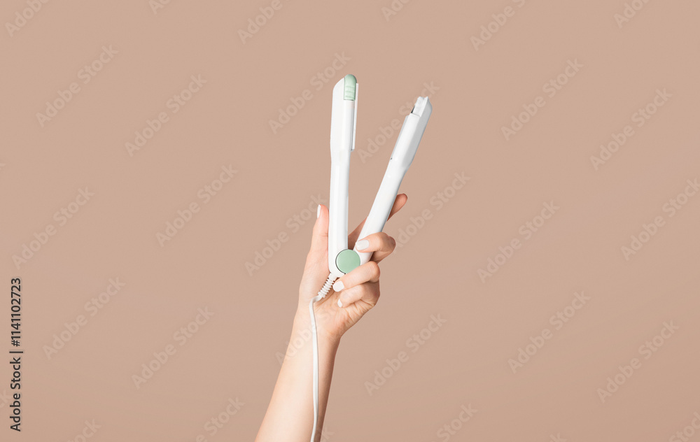 Millennial woman holding hair straightener on pink background, closeup. Panorama Millennial woman holding hair straightener on pink background, closeup. Panorama