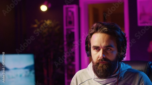 Close up shot of man putting headphones on while playing videogames at home to better immerse himself. Player participating in online multiplayer esports tournament, fighting to defeat enemies