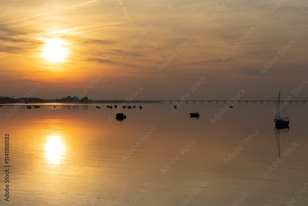 Tranquil water from a river at sunset with small recreational or sport boats Tranquil water from a river at sunset with small recreational or sport boats