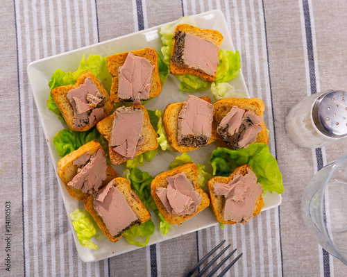 There are sandwiches with meat pate and china cabbage leaves on plate. Homemade snack for picnic, buffet. Mousse is made from chicken liver, spices, and butter. photo