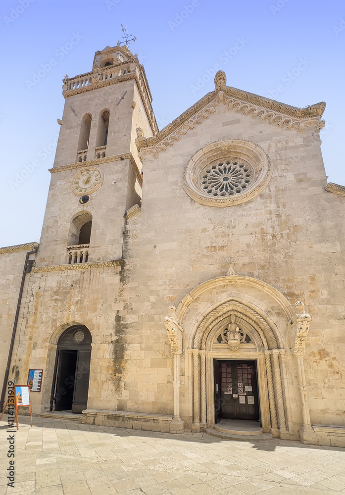 Korcula, Croatia - June 30, 2024: Front yellow stone facade and tower of Saint Mark Cathedral under light blue sky Korcula, Croatia - June 30, 2024: Front yellow stone facade and tower of Saint Mark Cathedral under light blue sky