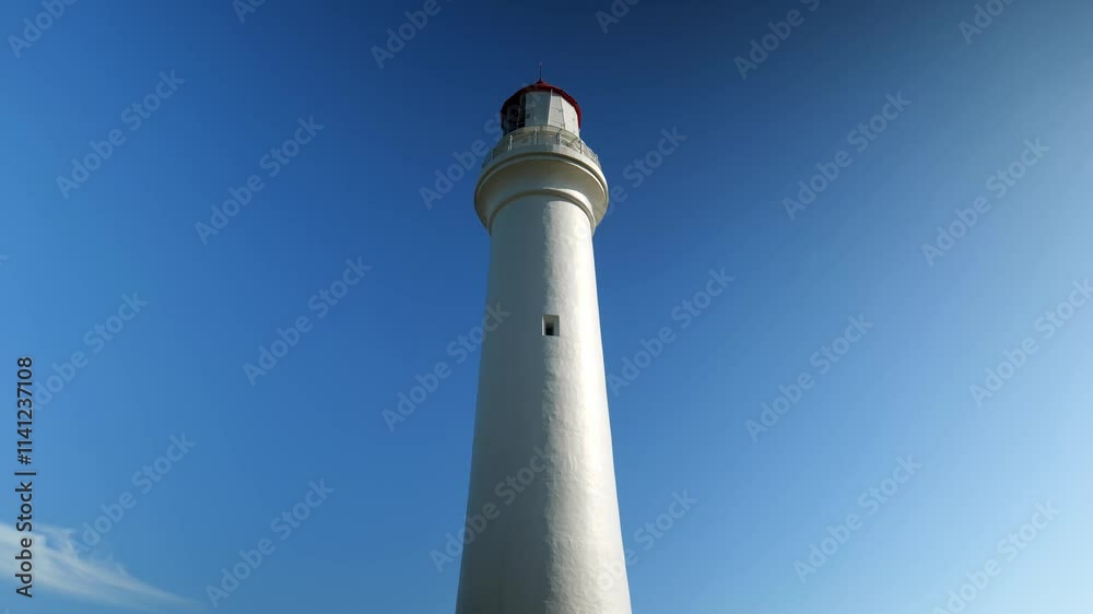 A lighthouse centered in the frame, standing tall against the backdrop of a vast ocean and clear sky, surrounded by rugged coastal terrain. A lighthouse centered in the frame, standing tall against the backdrop of a vast ocean and clear sky, surrounded by rugged coastal terrain.