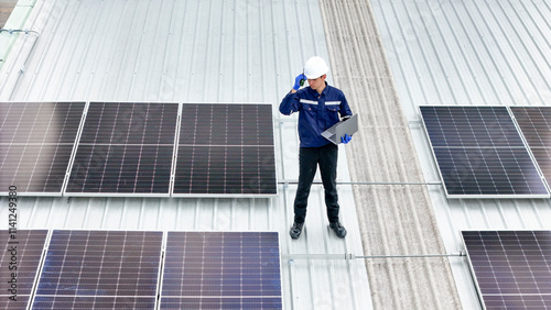 Wallpaper Mural technician in hard hat and safety gear inspects solar panels on a metal rooftop, holding a tool. The scene emphasizes renewable energy, solar technology, and maintenance of sustainable infrastructure. Torontodigital.ca