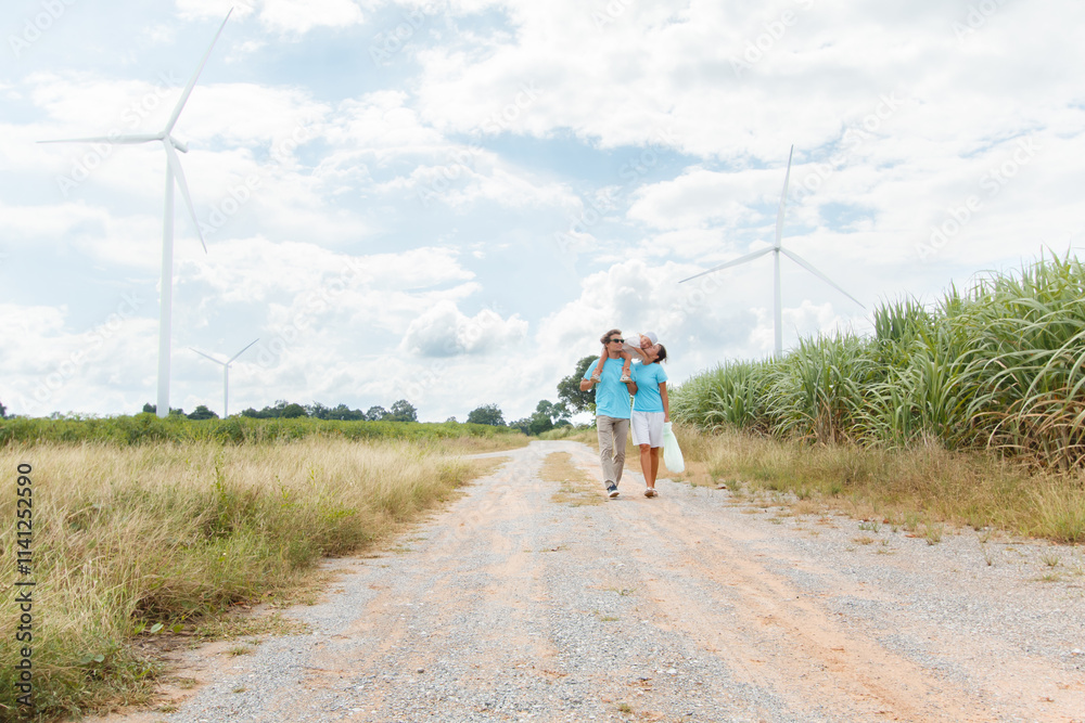 Obraz premium Happy cheerful caucasian white family with daughter are walking and relaxing together in the daytime in nature with windmill towers in background. Happy family activity concept.