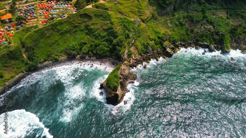 Aerial drone view of coastline with hills and trees, as well as view of coral cliffs and sea with waves from the ocean in Menganti Beach Kebumen Central Java Indonesia photo