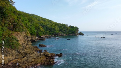 Aerial drone view of coastline with hills and trees, as well as view of coral cliffs and sea with waves from the sea in Pedalen Beach Kebumen Central Java Indonesia photo