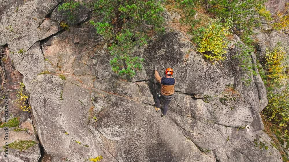Mountaineer use rope and carabiner equipment to climb steep cliff, Czechia Mountaineer use rope and carabiner equipment to climb steep cliff, Czechia