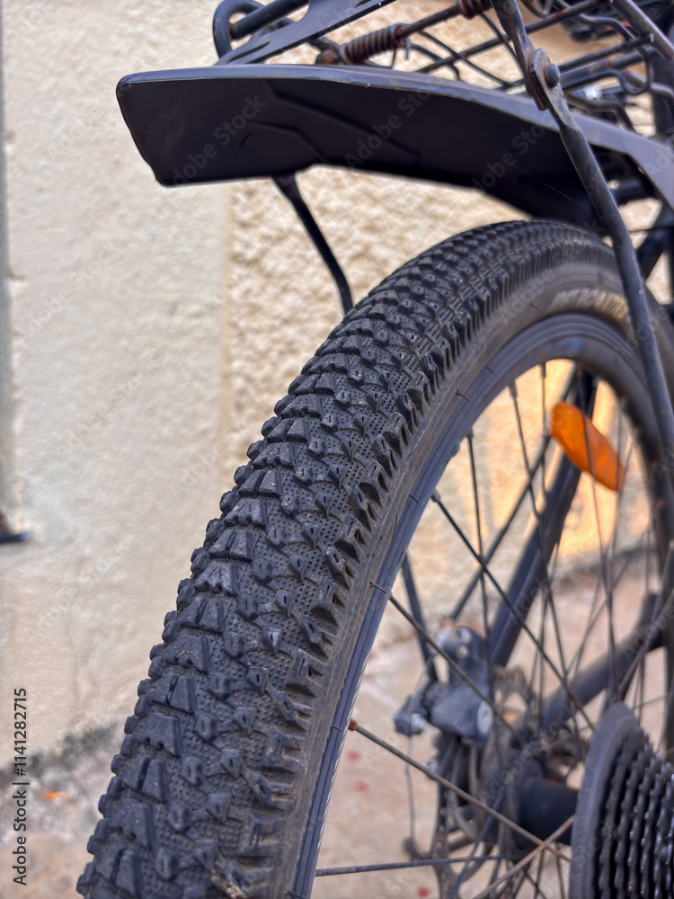 A black bicycle with a black tire and orange reflector A black bicycle with a black tire and orange reflector