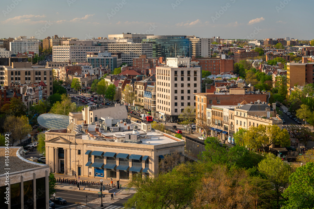 Fototapeta premium A scenic view of a vibrant urban landscape with historic architecture, tree-lined streets, and modern buildings is seen in a city center during sunset.