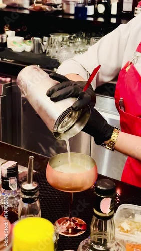 A professional bartender is preparing an alcoholic cocktail with ice cubes to customers at the bar or disco club.