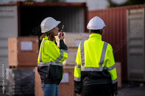 Engineer or dockworker working in the construction container dock yard checking and inspection containers data on computer program environment is container shipping Logistics business concept.