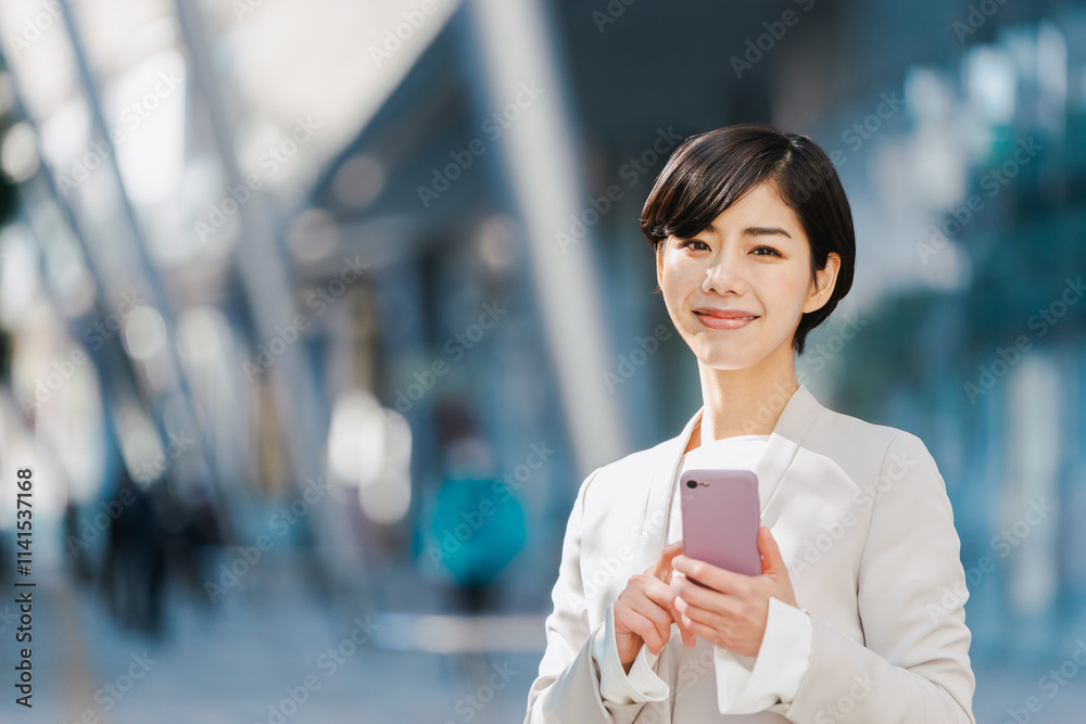 スマートフォンを持つスーツ姿の女性 スマートフォンを持つスーツ姿の女性