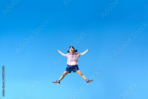 Wallpaper Mural 青空を背景に手足を広げジャンプをする幼い女の子1人 Torontodigital.ca