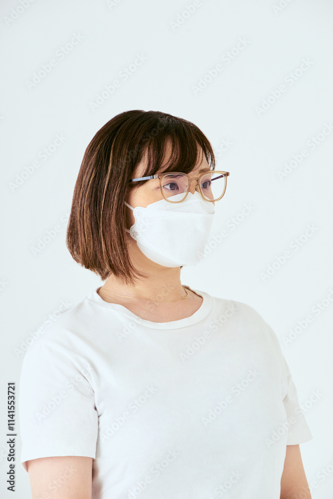 白背景でマスクと眼鏡を着けた右側を向いた30代の1人の日本人女性の人物の上半身 白背景でマスクと眼鏡を着けた右側を向いた30代の1人の日本人女性の人物の上半身