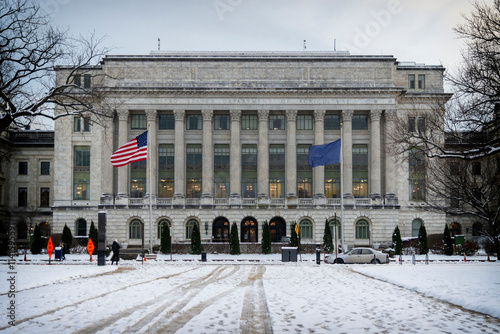 Close-up view of the USDA building in winter with snow-covered grounds, American and department flags, and historic architecture in Washington, D.C. photo