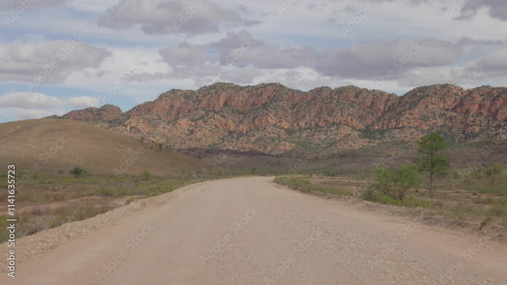 A dirt path cuts through the Australian outback, leading the eye towards a distant mountain range in Flinders Ranges A dirt path cuts through the Australian outback, leading the eye towards a distant mountain range in Flinders Ranges