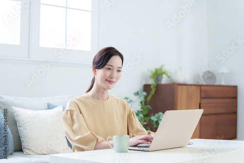 家でパソコンを使って仕事する女性