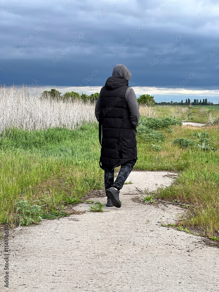 Man in dark coat walking in field, rear view. Man in dark coat walking in field, rear view.