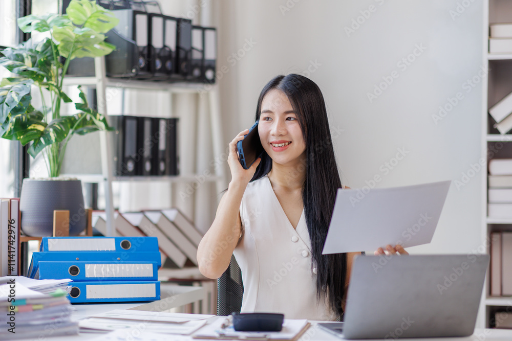 Businesswoman sitting at desk in bright office, talking on mobile phone and smiling.
Businesswoman sitting at desk in bright office, talking on mobile phone and smiling.