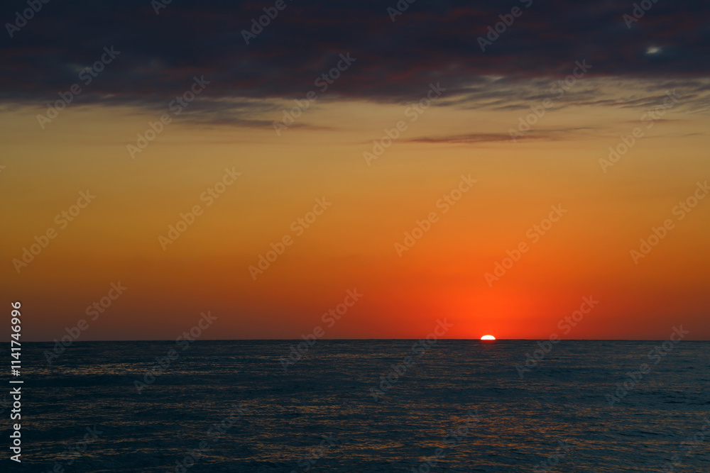 yellow Red evening sunset on dark sunset sea background. golden red disk gradient with sun path on waves descends beyond horizon line and dark sunrise sky. nature background. yellow Red evening sunset on dark sunset sea background. golden red disk gradient with sun path on waves descends beyond horizon line and dark sunrise sky. nature background.